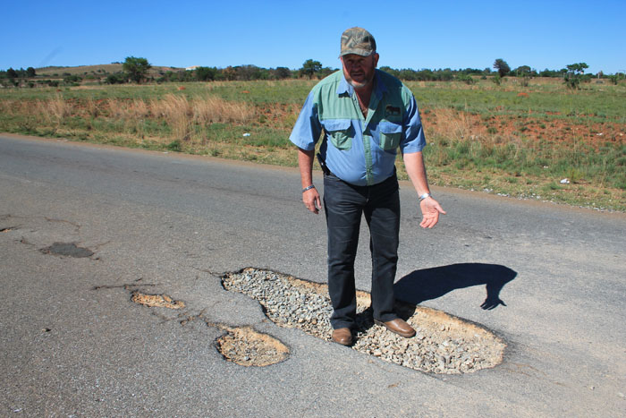 Mr Ben van den Berg shows the deep hole at which a motorist damaged his vehicle last week.