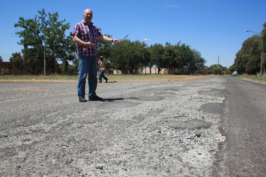 Mr Carlos Rebelo shows the disintigrating road surfae in the busy Van der Westhuizen Street.