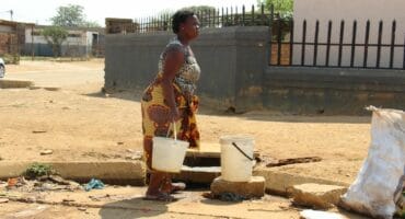 Many residents in Kokosi still have no water, which has forced people such as this woman to get water from a manhole on the sidewalk at Extension 1 near the ZCC Church.