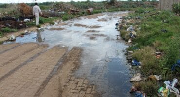 A resident walks past the road to the transfer station that is flooded with sewage.