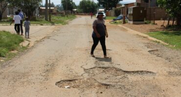 A pedestrian walking past one the many potholes in Patrys Street.