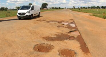 A motorist driving around some of the potholes on the main road through Welverdiend.