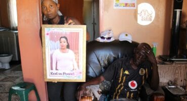 Lerato Gumede, a friend of the late Dikeledi Emily Mathabela holds her photo while the victim's uncle, Samuel Fihla, looks on..