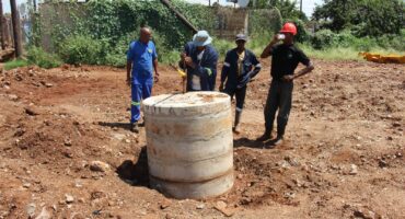 Employees of the municipal contractor looking at the new manhole, which is already starting to sag due to the constant sewage leaks under it.