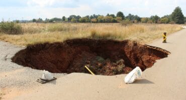 The sinkhole that caved in onto the tarred road surface has grown to such an extent that the Goudvlakte sign has fallen into it. Photo: Adele Louw (Carletonville and Fochville Herald)