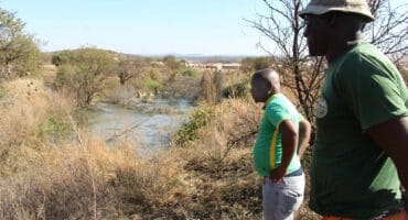 Concerned residents Lunga Zituta and Mike Mohoza looking at a dam of sewage behind Wedela Extension 1. Photo: Adele Louw (Carletonville and Fochville Herald)