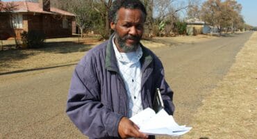 Mzwandile Kheswa, with proof of the alleged bribery, is standing in Geldenhuys Street near where the problems occurred. Photo: Adele Louw (Carletonville and Fochville Herald)