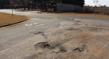 The faded stop sign and potholes on the road surface at the corner of Caledon and Vaal Streets. Photo: Adele Louw (Carletonville and Fochville Herald)