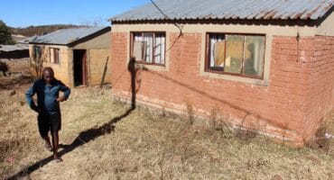 Zituta walks past another empty house. The house next to it has already been occupied by a resident previously looking for a home. Photo: Adele Louw (Carletonville and Fochville Herald)