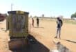 Concerned residents looking at a damaged electricity box with the Khutsong hostels in the background. Photo: Adele Louw (Carletonville and Fochville Herald)