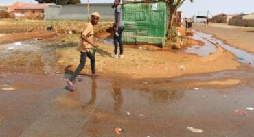 Nelson Hlongwane and Donald Mohlamme making their way over the sewage leak at the corner of Hornbill and Spaniel Street.