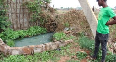 One of the helpers, Thabang Buchingi, shows how community members have dammed up the sewage at the leaking manhole. Photo: Adele Louw (Carletonville and Fochville Herald)