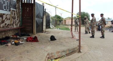 SANDF members standing in front of the tavern. Shoes and other belongings of the deceased and injured were still lying on the stoep. Photo: Adele Louw (Carletonville and Fochville Herald)
