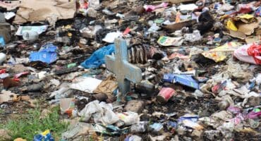 A gravestone barely sticking out of the rubbish. Photo: Adele Louw (Carletonville and Fochville Herald)