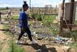 Lerato Gumede shows where sewage is streaming from a manhole in Kokosi Ext 99. Photo: Adele Louw (Carletonville and Fochville Herald)
