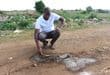 Welile Fihla shows the water pipe that the zamazamas dug out in the middle of a street. Photo: Adele Louw (Carletonville and Fochville Herald)