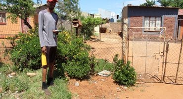 Thapelo Mohlahatsa shows where criminals stole his family’s water meter about two weeks ago. Insert: Some residents have even bought replacement globes themselves, but are not getting help from the municipality to install them. Photo: Adele Louw (Carletonville and Fochville Herald)