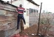 Pule Faku shows where he jumped over his back fence to avoid the attackers. Photo: Adele Louw (Carletonville and Fochville Herald)