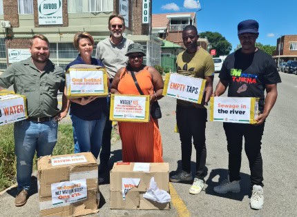 Lede van die burgerregte organisasie AfriForum, saam met lede van die gemeenskapsorganisasie Metsi Pompong by van die bokse wat hulle aan die Ngwathe burgemeester wou oorhandig.