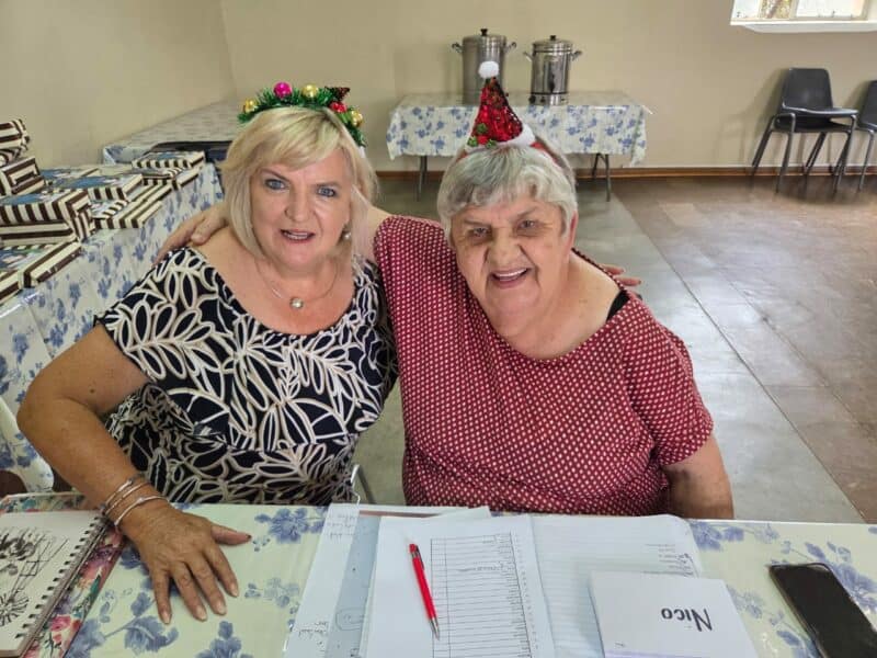 Women celebrating Christmas together in a festive setting.(regs) wat al Hart en Siel se administrasie behartig. Foto: Verskaf