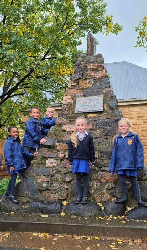 Van die graandeens van Primêre Skool Parys by die klipstapel-monument naby die skoolsaal van Hoërskool Parys. Hulle sal in hul matriekjaar die boodskappe lees wat 100 jaar gelede deur matrikulante in die monument geplaas is. Foto: Liezl Scheepers