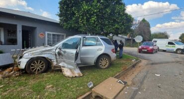Een van die voertuie is met die impak van die botsing in 'n steen- en palisade omheining in van 'n hoekhuis by die kruising. Foto: Liezl Scheepers