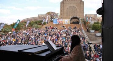 Chanie Jonker, musiekregisseur van Gé Sing: Hoor my Lied!, op klavier met die Voortrekkermonument in die agtergrond. (Foto: Niël Langner)