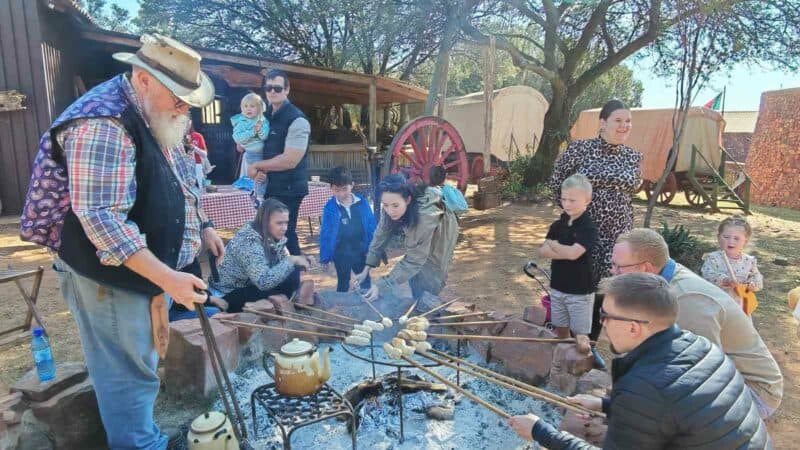 Kinders en hul ouers maak saam stokbrood om die kampvuur in die Lewende Laer. (Foto: Du Preez de Villiers)