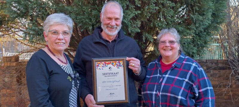 ‘n Trotse Erna Rademan en Wynand en Elsje Serfontein met die toekenning wat aan die ATKV Vredefort Koepel-tak oorhandig is.