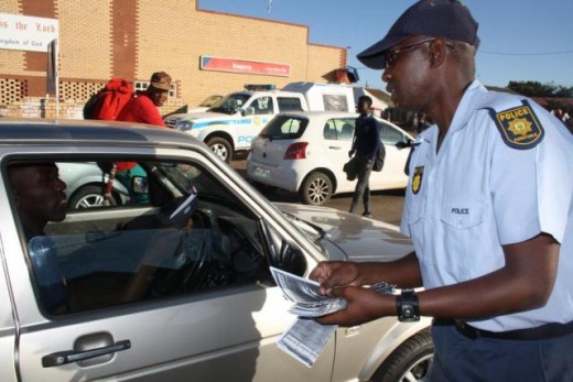 Const Mosiane Moeketsi hands out a flyer to a passing motorist. Photo: Selogile Leshage