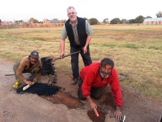 Gewone mense maak buitengewone verskil. Dirkie Venter, Ben en Marthenus Jansen van Rensburg maak slaggate in MC Roodeweg reg. Foto: Tommie de Beer