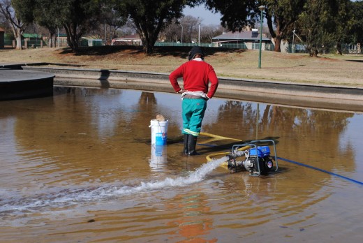 Die vuil water word uit die dammetjie uit gepomp sodat die bodem skoongemaak kan word.