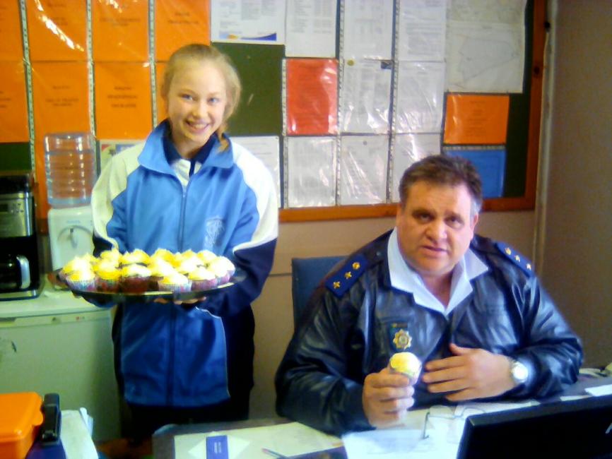 The Ikageng station commander, Col Brazer happily accepts a cupcake.