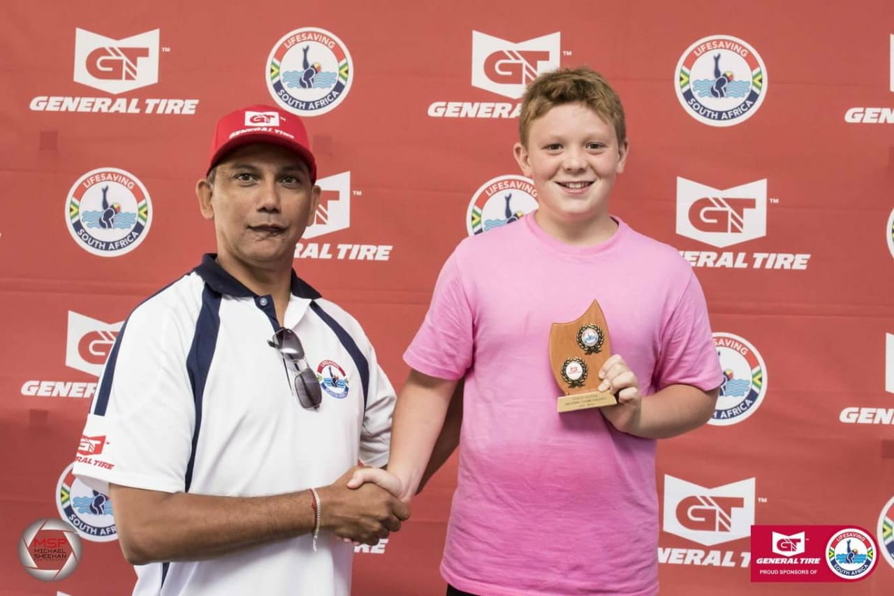 Lifesaving South Africa (LSA) president, Dylan Tommy awarding Aiden Nel with the Victor Ludorum trophy.