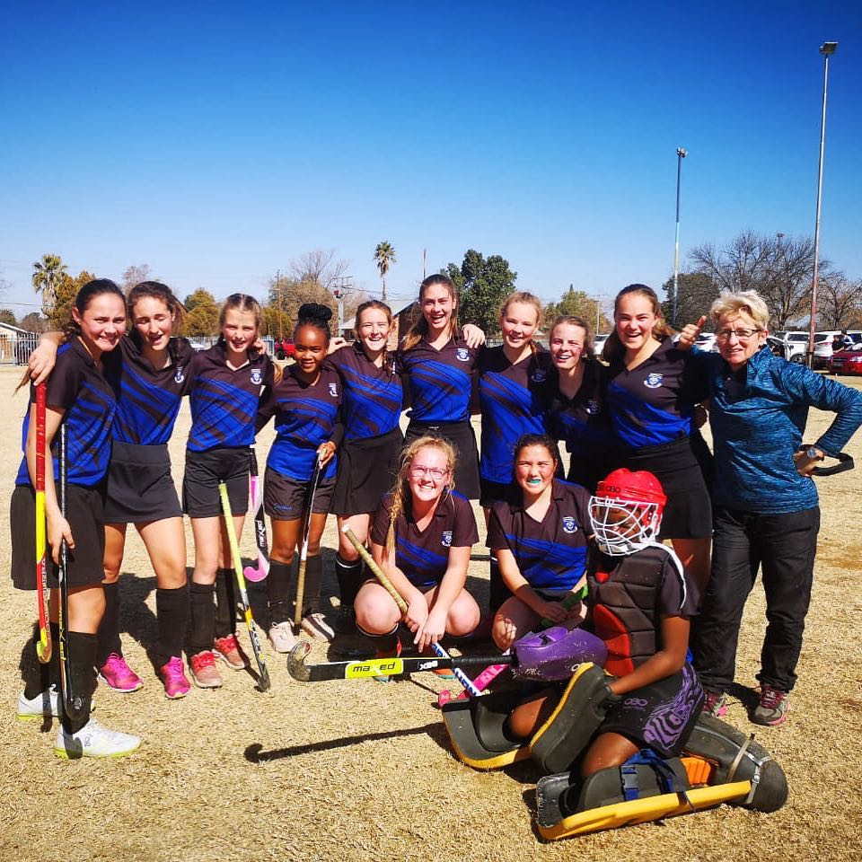 Ferdies se grys juniorspan speel tans kookwater hokkie in die Monsantoliga. Hier is die span saam met hul afrigter, mej. Sanet Meiring.