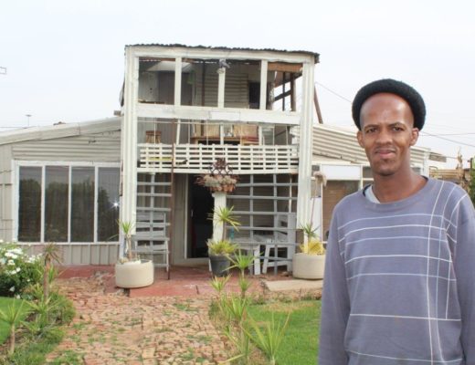 Thabo voor sy byna volledige droomhuis. Hy het alles met sy eie twee hande gebou.