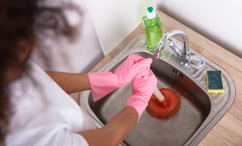 Close-up,Of,A,Female,Plumber,Wearing,Pink,Gloves,Using,Plunger