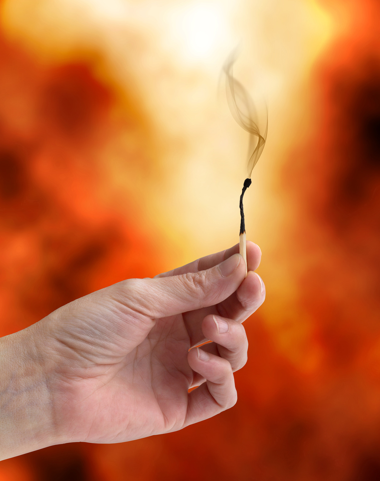 hand holding an extinguished matchstick on a fiery background, fire, ER24