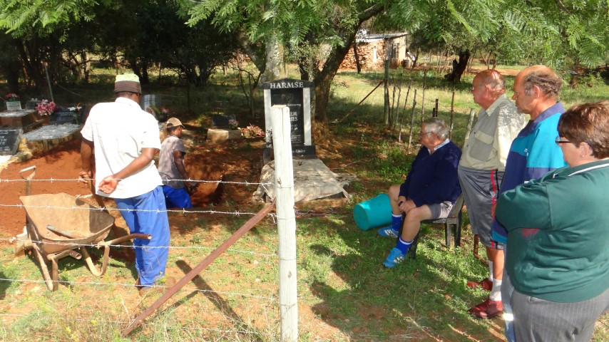 Bo: Familie, vriende en boere van die Parysomgewing kyk toe terwyl werkers die graf grawe op die familieplaas waar wyle mnr. Frans Harmse se vrou ook begrawe is. Die begrafnis vind Vrydag plaas. Hy het na ‘n plaasaanval aan sy beserings gesterf. Foto: Jannie du Plessis.