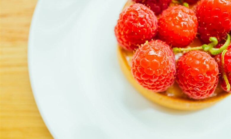Sweet dessert custard tart with raspberry on top in white plate