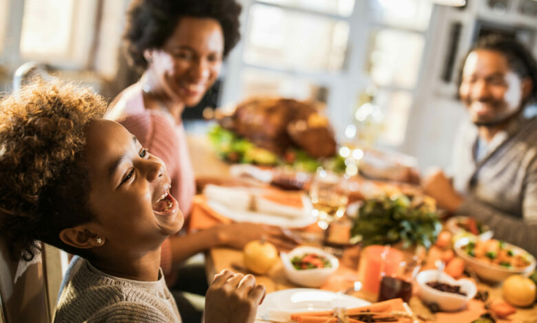 Cheerful African American girl with her parents at dining table.