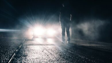 eugene-triguba-XIx85KpKmWU-unsplash lights shining on person in rain
