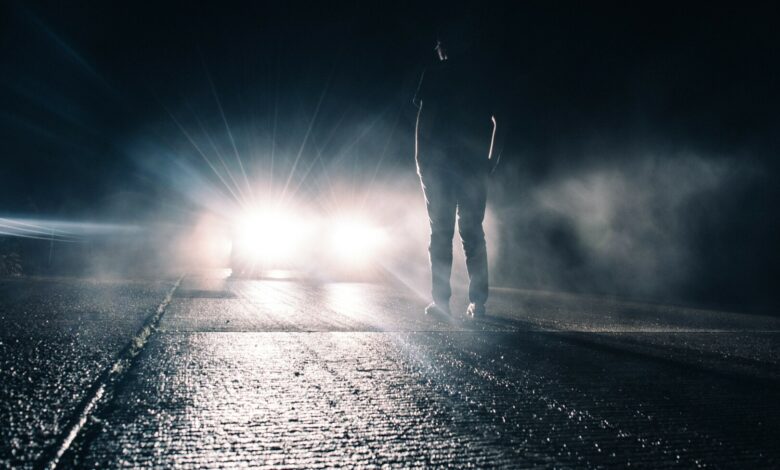 eugene-triguba-XIx85KpKmWU-unsplash lights shining on person in rain