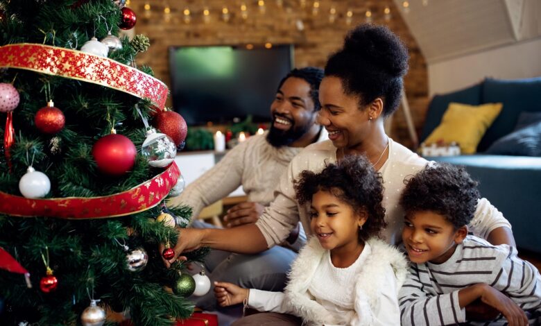Happy African American family decorating Christmas tree at home.