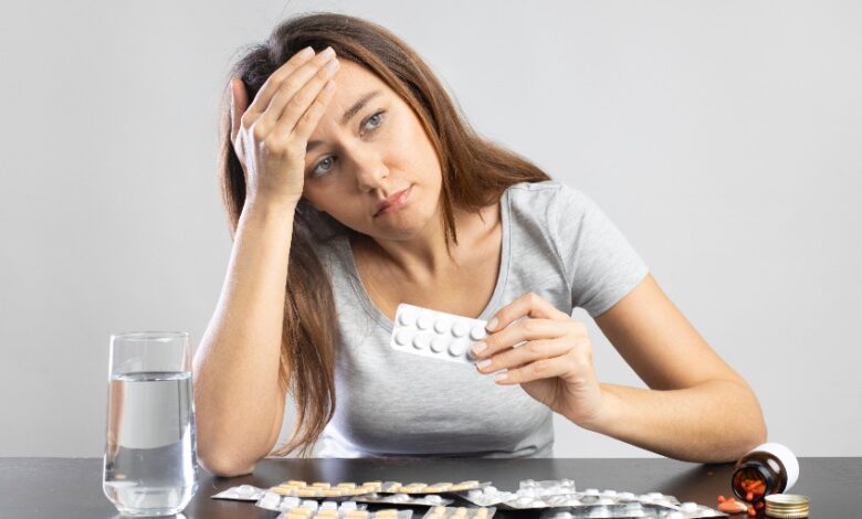 Young woman suffering from headache holding pills in her hand