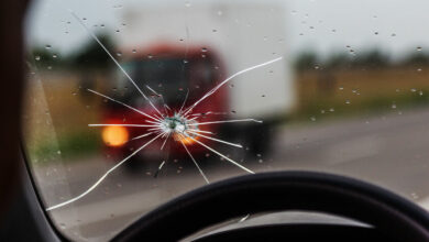 Broken windshield of a car. A web of radial splits, cracks on the triplex windshield. Broken car windshield, damaged glass with traces of oncoming stone on road or from bullet trace in car glass
