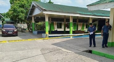 Policemen stand near the crime scene of a school compound after a shooting incident at a high school compound in Tacloban City, Leyte province on June 22, 2026.
