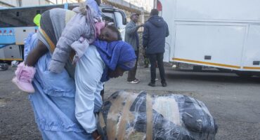 A Malawian woman repatriated from South Africa pushes her luggage while holding a girl on her back at Kamuzu stadium, the country's receiving camp on Thursday. Photo: AFP