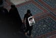 A boy holds a portrait of Iran's slain supreme leader Ali Khamenei as clerics wait to hold prayers over his coffin at Imam Ali Shrine in Najaf on July 8, 2026, before it was carried on to the Iraqi holy city of Karbala.