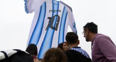 Argentina fans gather beneath a giant Argentina jersey bearing Lionel Messi's number 10 displayed in front of the National Flag Memorial in Rosario, Santa Fe province, Argentina, on July 18, 2026, ahead of the 2026 FIFA World Cup final between Argentina and Spain on July 19. (Photo by Marcelo Manera / AFP)
